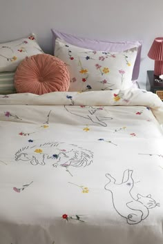 a bed with an embroidered comforter and pillows on it, next to a lamp