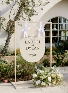 a sign that says laurel and dylian on it with flowers in front of the building