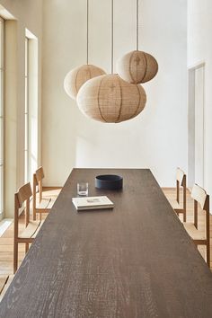 a wooden table topped with a book next to two hanging light fixture's over it