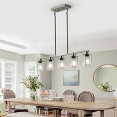 a dining room table and chairs with lights hanging from the chandelier over it