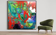 an abstract painting hangs on the wall next to a green chair