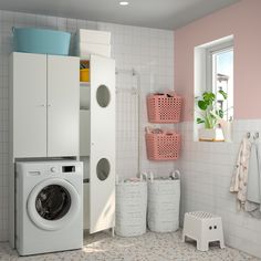 a washer and dryer in a small room with pink walls, tile flooring and white cabinets