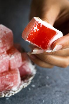 a person holding a piece of food in their hand and some sugar cubes on the other side