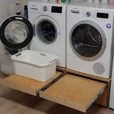 two washers and a dryer sitting on top of a wooden shelf