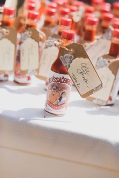 several bottles of hot sauce on a table with tags attached to them and some empty ones in the background