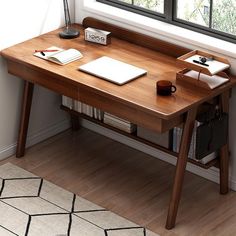 a wooden desk with a laptop and books on it in front of a large window