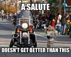 a police motorcycle driving down a street next to a woman on the side of the road