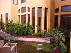 an outside view of a building with red flowers in the foreground and green grass on the ground