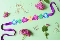 flowers and ribbons on a green surface with confetti sprinkled around them