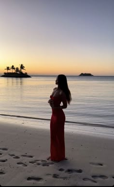 a woman in a red dress standing on the beach