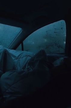 a person sleeping in the back seat of a car with their head up on a blanket