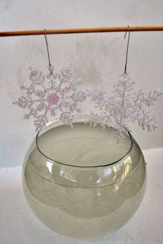 a glass vase with snowflakes hanging from it