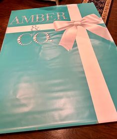 a large blue gift bag with white ribbon and name on the front that says ambree co