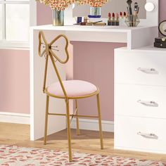 a pink chair sitting in front of a white desk with flowers on top of it