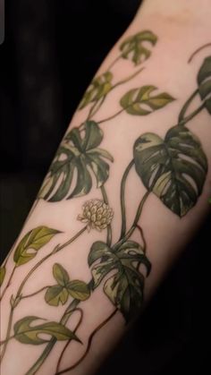 a close up of a person's arm with flowers and leaves on it