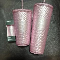 two pink tumblers are sitting next to each other on a black surface with a green tag