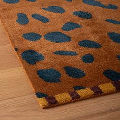 a brown rug with blue spots on it sitting on a wooden floor next to a lamp