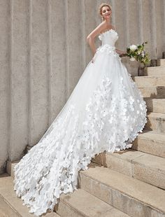 a woman in a wedding dress standing on some steps