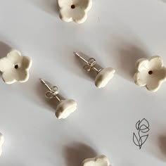 several white flower shaped earrings are shown on a sheet of paper with the word love written below them