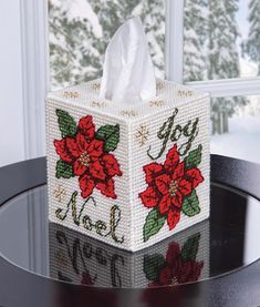 a tissue box decorated with poinsettis and the words joy noel