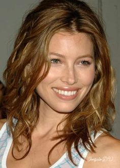 a close up of a person wearing a tank top and smiling with her hair in the wind