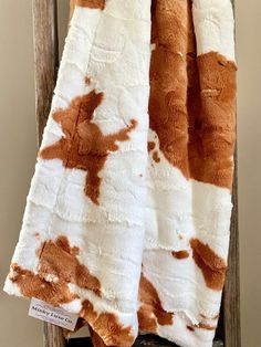 a brown and white cow print blanket sitting on top of a wooden chair