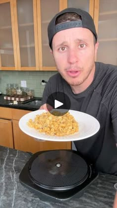 a man holding a plate with food on it in front of a stove top oven