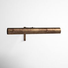 an old brass pipe is hanging on the wall in front of a white wall with no one around it