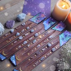 a wooden table topped with lots of different types of rocks and stars next to a candle