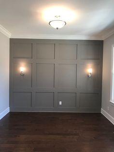 an empty room with some lights on the wall and wood floors in front of it