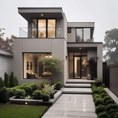 a modern house with lots of windows and plants in the front yard