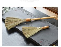 two wooden brooms sitting on top of a black table next to a gray tray