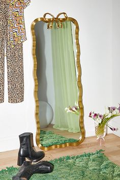 a pair of black boots sitting on top of a green rug in front of a mirror