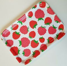 a red and white tray with raspberries on it, sitting on a table