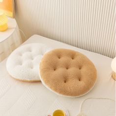 two round cushions sitting on top of a bed next to a cup and saucer