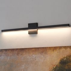 a wall light that is mounted on the side of a wall next to a painting