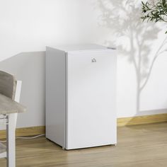 a white refrigerator sitting next to a table with a potted plant on top of it