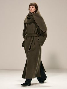 This luxurious double-breasted coat crafted from 100% wool features a versatile shawl collar that can be styled as a dramatic cape, complete with a detachable belt for a customized silhouette. The maxi-length design offers superior warmth and sophistication, while thoughtful details like side slit pockets, hidden snap closures, and a full twill lining elevate its collectible appeal. Available in both khaki and black, this handmade piece combines timeless elegance with practical functionality, ma Fall Wool Coat With Shawl Collar, Elegant Long Khaki Outerwear, Elegant Khaki Pea Coat For Fall, Elegant Khaki Long Pea Coat, Elegant Long Khaki Pea Coat, Shawl Collar Coat, Collar Coat, Collared Coat, Camel Coat