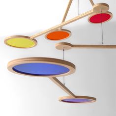 an assortment of circular wooden objects hanging from the ceiling, with colored circles on them