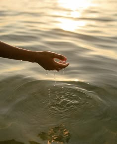 a person's hand reaching out to the water