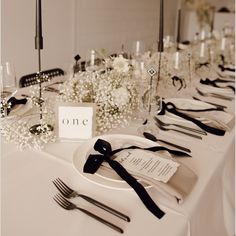 the table is set with black and white flowers, silverware, and napkins