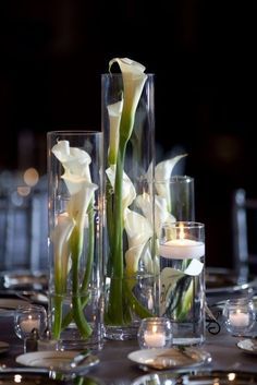 there are two vases with flowers and candles on the table