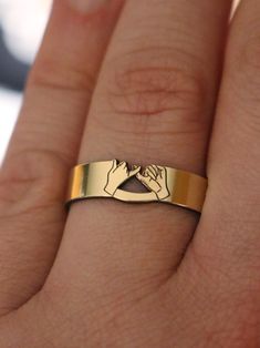 a person's hand with a gold ring on it