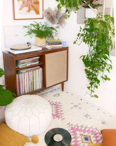 a living room with various plants and records on the shelf next to an old record player