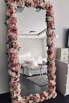 there is a mirror with flowers on it and the reflection of a couch in the mirror