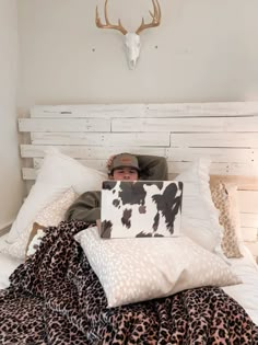 a man laying in bed with a laptop on his chest and cow head above him