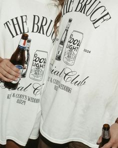 two people standing next to each other holding beer bottles