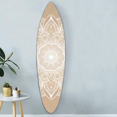 a surfboard is hanging on the wall next to a table and potted plant