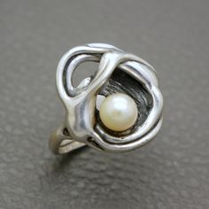 Showcase your love for unique jewelry with this stunning Modernist Design Sterling Silver Ring, featuring a natural cultured saltwater pearl. The abstract and expressive design of this piece makes it a standout addition to any jewelry collection. This high-quality, artisan handcrafted ring originates from the 1970s to 1980s era, showcasing the creative vibrant aesthetic of its time. It will be shipped in a gift box and makes for a thoughtful gift! Ring size: US: 8 1/4, UK: Q 1/2, European size: Artisan Untreated Jewelry For Wedding, Artisan Untreated Wedding Jewelry, Modernist Ring Jewelry For Anniversary, Modernist Hallmarked Wedding Rings, Modernist Sterling Silver Wedding Rings, Unique Handmade Pearl Ring For Anniversary, Art Nouveau Sterling Silver Rings As Gift, Art Nouveau Sterling Silver Rings As A Gift, Vintage Wedding Rings With Unique Design