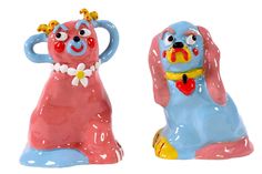 two ceramic figurines that look like dogs with flowers on their heads, one is pink and the other blue